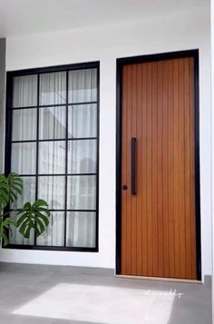 a house with two windows and a wooden door in front of the window is a potted plant