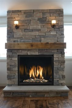 a stone fireplace with two lights on each side and some logs in the middle that are lit up