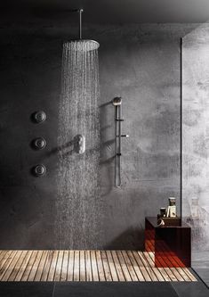 a shower head with rain coming out of it in a bathroom next to a wooden floor