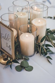 candles are arranged on a table with greenery