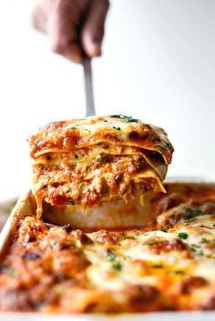 a person is holding a fork in a lasagna casserole dish