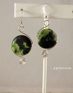 earrings with green and black marbles on them hanging from a white hook earring