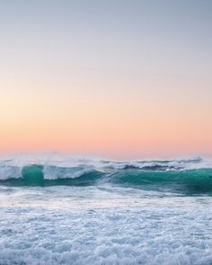 the sky is pink and blue over the ocean waves