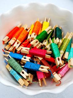 many different colored spools of thread in a bowl