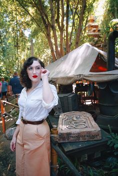 a woman standing in front of an old fashioned stove with red lipstick on her lips