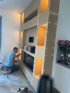 a man is working on a wall unit in the middle of a room that has been painted yellow