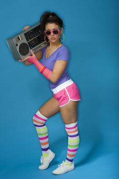 a woman in pink shorts and knee high socks holding an old school boombox over her head