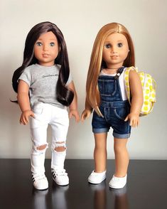 two dolls standing next to each other on a table