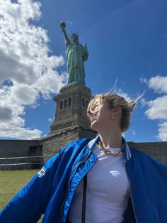 a woman standing in front of the statue of liberty