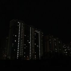 some buildings are lit up at night in the dark with white lights on them and there is no image to provide a caption for