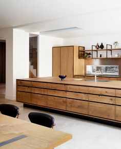 a large kitchen with wooden cabinets and black chairs in front of the counter top area