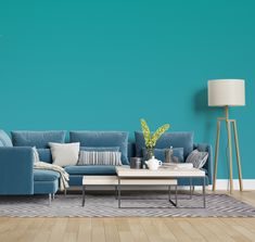 a living room with blue couches and white coffee table in front of a purple wall