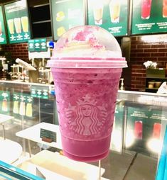 a pink starbucks drink sitting on top of a glass table in front of a display case