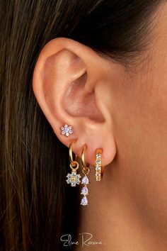 a close up of a woman's ear wearing gold earrings with flowers on them