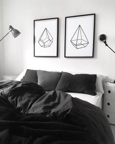 two black and white pictures hang on the wall above a bed in a bedroom with dark linens