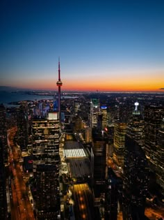 an aerial view of the city skyline at night with lights and skyscrapers in the foreground