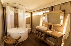 a bathroom with a bathtub, sink and mirror in the corner next to a wooden chair