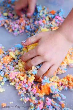 a child's hand reaching for colorful sprinkles on a table top