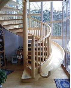 a spiral staircase in the middle of a living room next to a large glass window