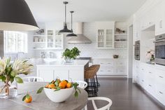 a bowl of fruit is sitting on a table in the middle of a large kitchen