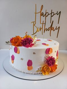 a birthday cake decorated with flowers and the words happy birthday written on top in gold lettering