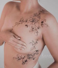 a woman with flowers on her chest is posing for the camera while holding her breast