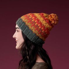 a woman wearing a multicolored knitted hat with pom - pom