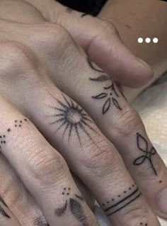 two fingers with tattoos on them, one has an arrow and the other has stars