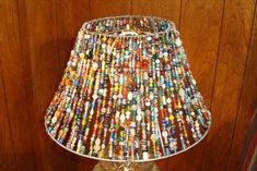 a lamp made out of bottle caps on top of a wooden table next to a wall