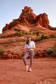 a woman in white shirt and leggings playing frisbee on dirt field