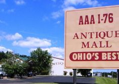 a sign for an antique mail shop in the middle of a parking lot with cars parked behind it