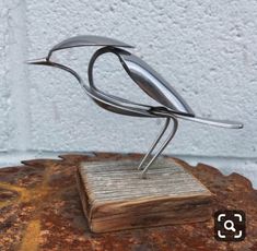 a metal bird sculpture sitting on top of a book