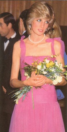 a woman in a pink dress holding flowers