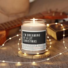 a lit candle sitting on top of a wooden table next to a string of lights