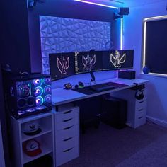 a computer desk with two monitors on top of it in front of a large screen