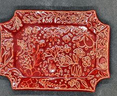 a red tray with flowers and leaves painted on the bottom is sitting on a gray surface