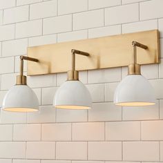 three lights are mounted on the wall above a sink