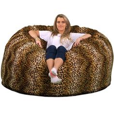 a woman sitting on top of a leopard print bean bag chair with her legs crossed