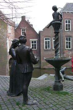 a statue of two people standing next to a fountain in the middle of a courtyard