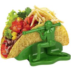 a green toy soldier holding a taco with fries and tomatoes on it's side