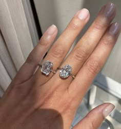 a woman's hand with two engagement rings on her left and one diamond ring on the right