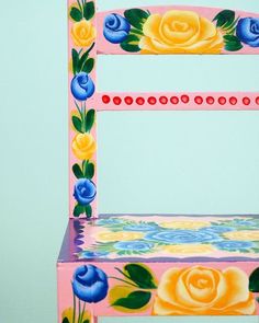 a painted wooden chair with roses on the back and sides, against a blue background