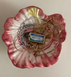 a pink flower shaped plate with charms and a badge on it that says hottie