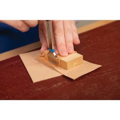 a person using a small tool to make a piece of wood on top of a table