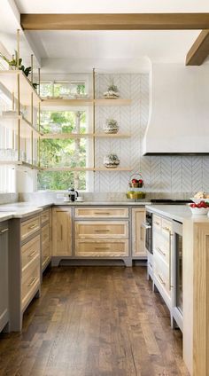 a kitchen with wooden flooring and white cabinets in the center, along with open shelving