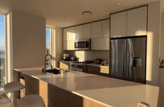 an empty kitchen with stainless steel appliances and large windows overlooking the cityscape in the background