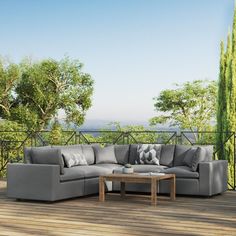 a large gray couch sitting on top of a wooden floor next to a tree filled forest