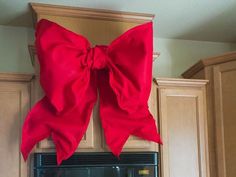 a large red bow hanging from the side of a kitchen cabinet over a stove top