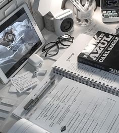 an open book sitting on top of a desk next to a laptop computer and other items