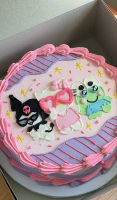 there is a cake in the box that has decorations on it, and two cats